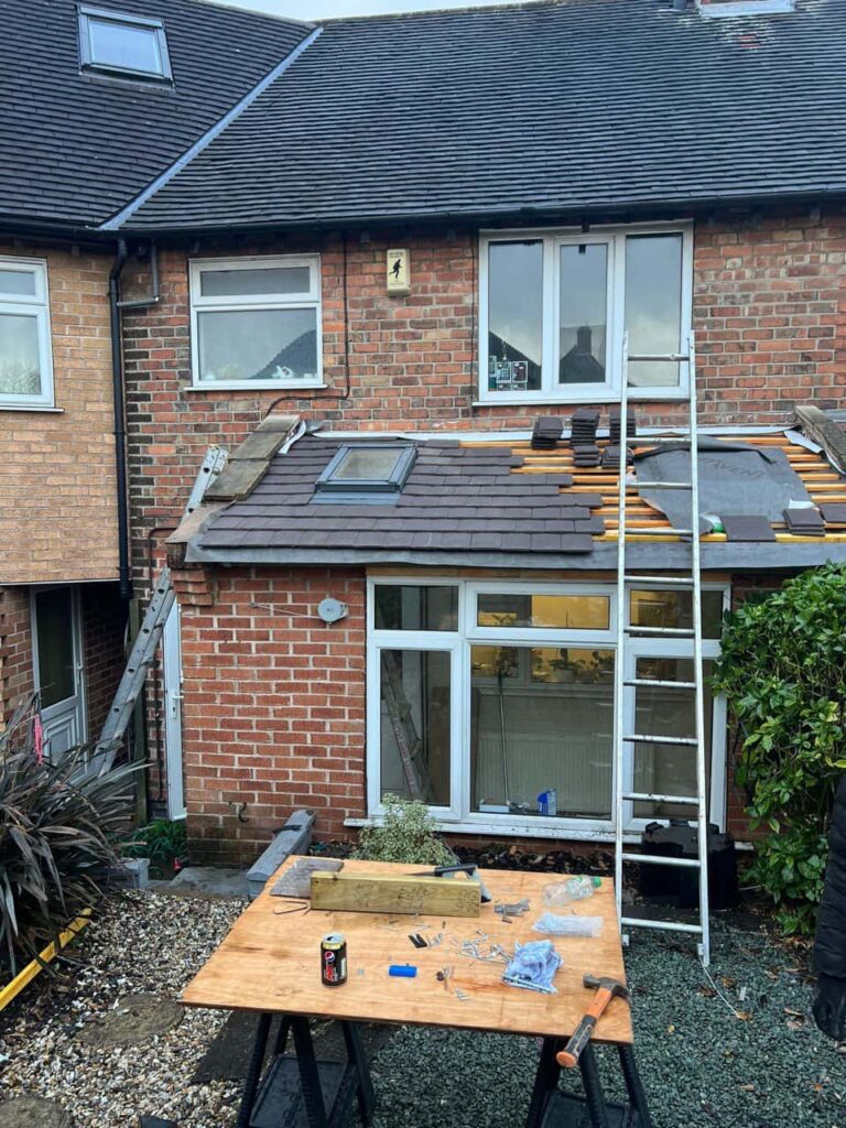 This is a photo of a roof extension that is having new roof tiles installed. This is a photo taken from the roof ridge looking down a tiled pitched roof on to a flat roof. Works carried out by Oxted Roofing Repairs