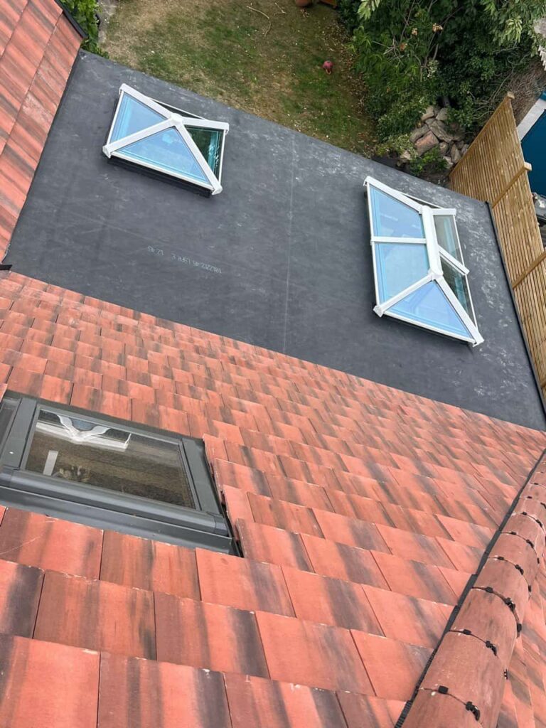 This is a photo taken from the roof ridge looking down a tiled pitched roof on to a flat roof. Works carried out by Oxted Roofing Repairs